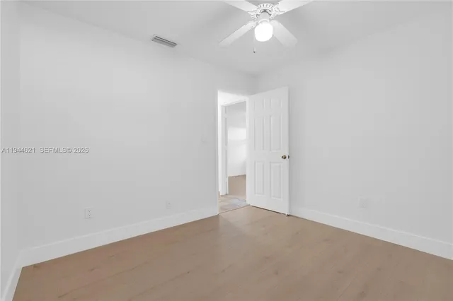 an empty room with a chandelier fan and closet