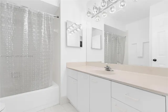 a bathroom with a granite countertop sink a mirror a bathtub and shower