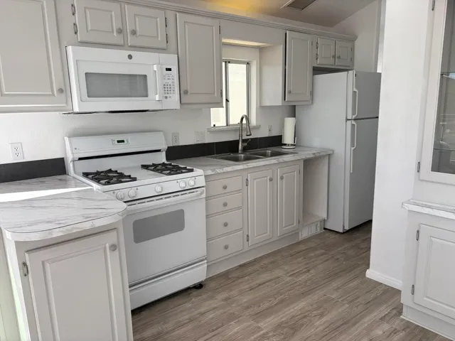 a kitchen with granite countertop white cabinets and white appliances