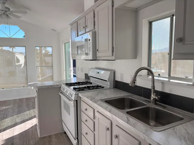 a kitchen with stainless steel appliances granite countertop a sink and a stove next to a window