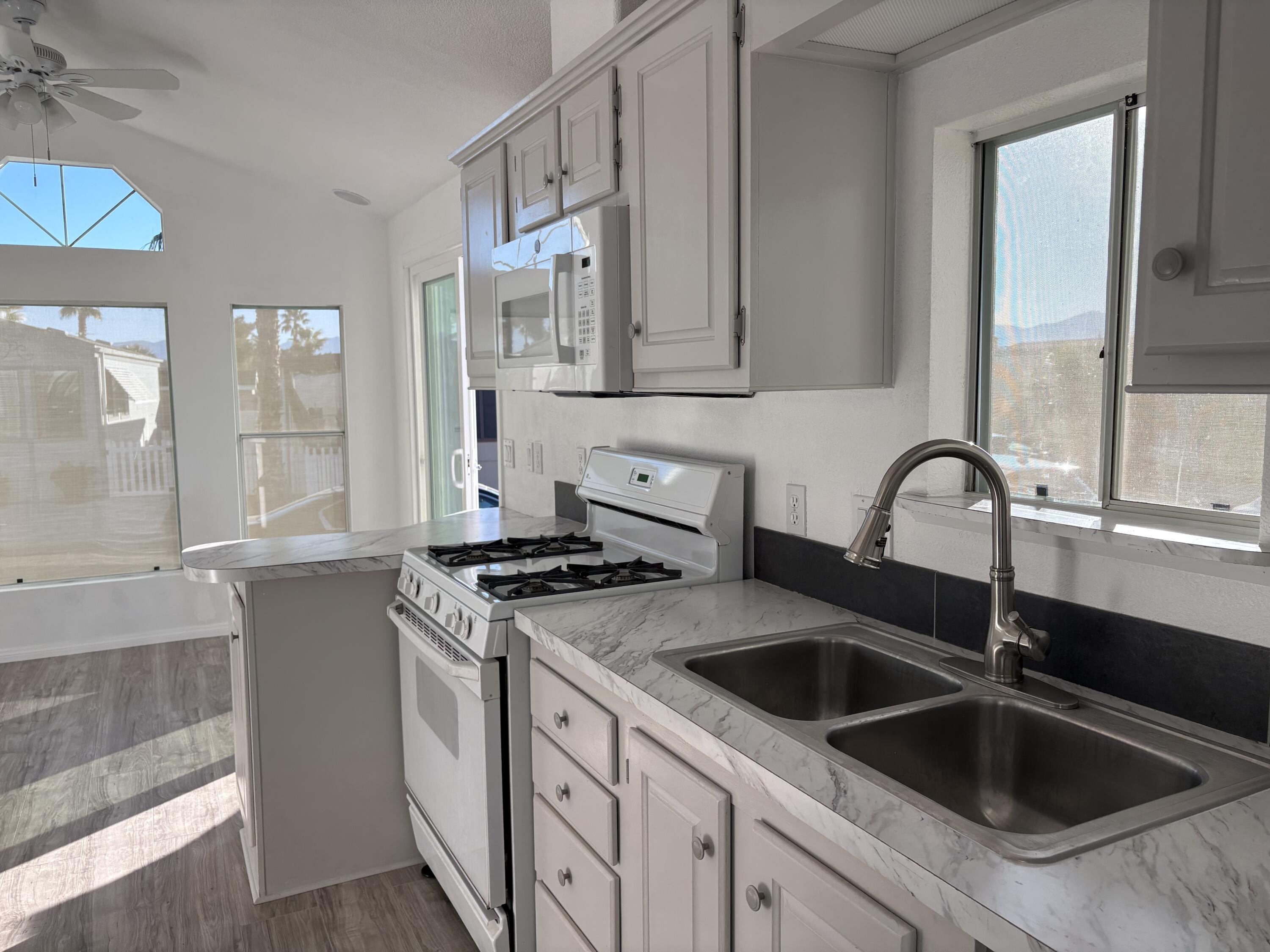 74711 Dillon Road, Unit 819 Desert Hot Springs, CA 92241 - Photo 7 of 41 a kitchen with stainless steel appliances granite countertop a sink and a stove next to a window