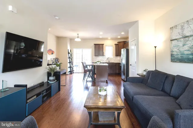 a living room with furniture kitchen view and a flat screen tv