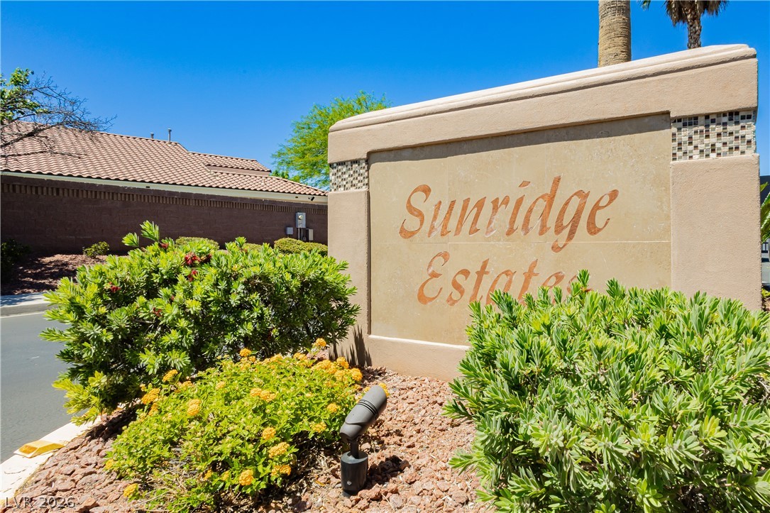 2256 Dogwood Ranch Avenue Henderson, NV 89052 - Photo 6 of 51 An inviting entry to Sunridge Estates, featuring lush landscaping and tile-roofed structures under a bright sky.