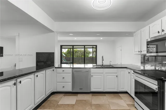 a kitchen with granite countertop white cabinets and white appliances