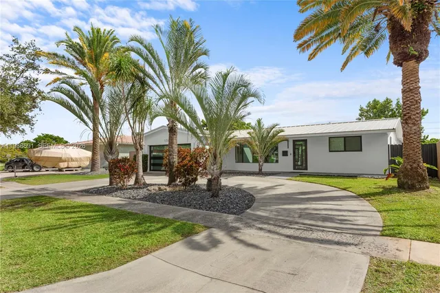 a front view of a house with garden and trees