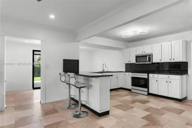 a kitchen with granite countertop white cabinets and stainless steel appliances