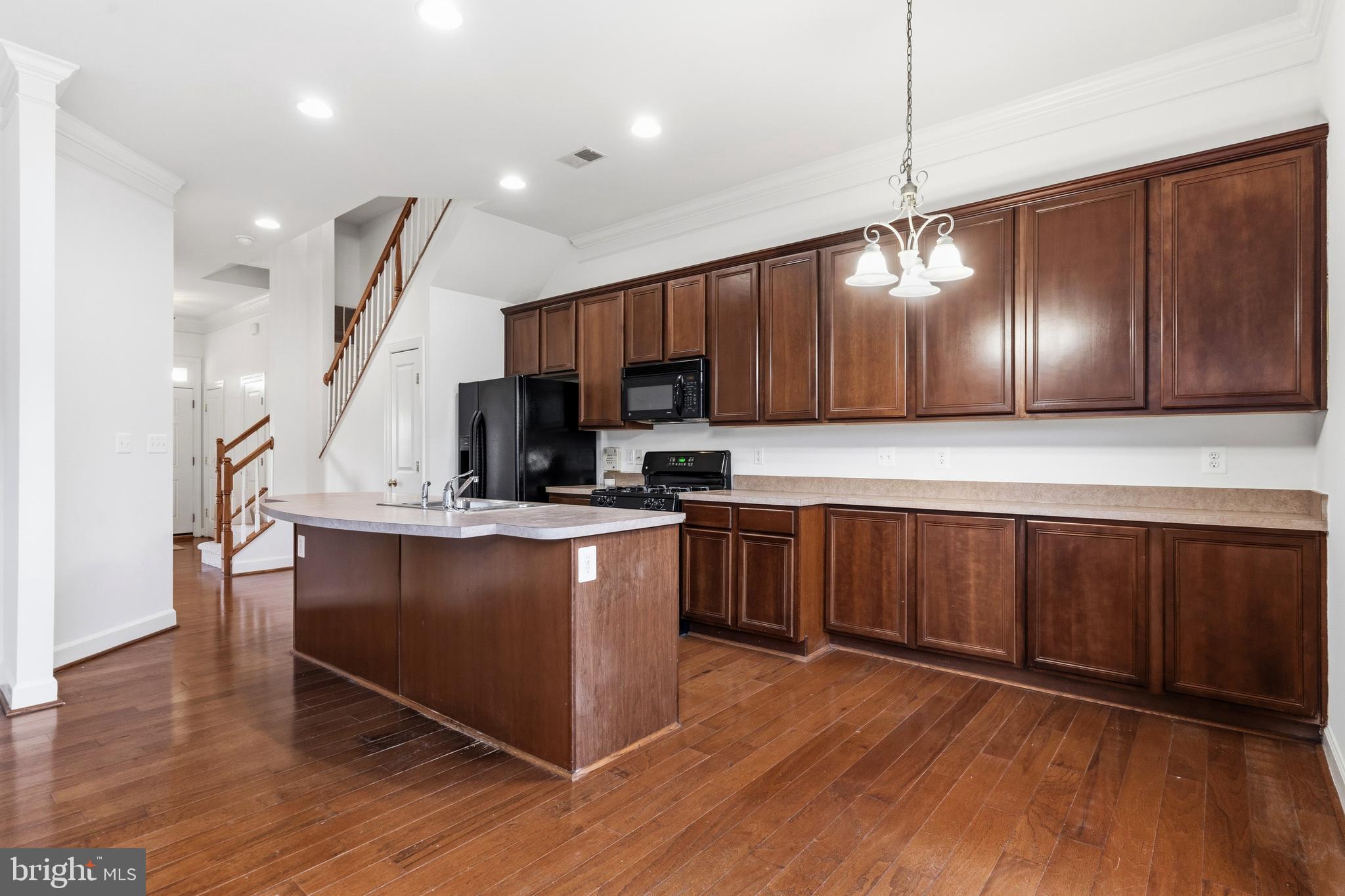 9227 Ribbon Falls Loop Bristow, VA 20136 - Photo 20 of 53 a kitchen with stainless steel appliances wooden floors wooden cabinets a refrigerator and microwave
