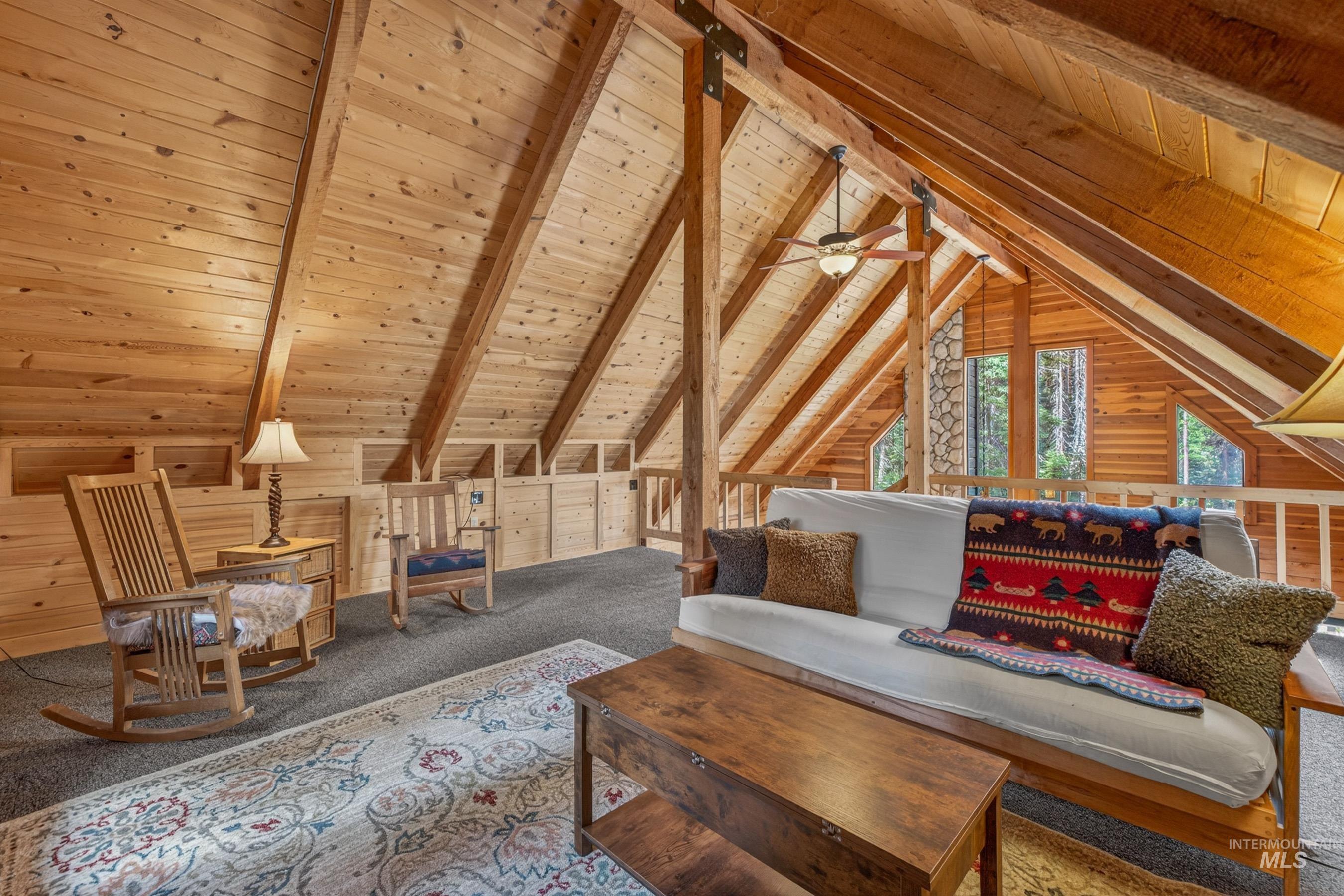 2339 West Mountain Road Donnelly, ID 83615 - Photo 11 of 37 Vaulted wood-paneled ceiling with exposed beams, wood-plank walls, multiple windows, and a ceiling fan with light fixture
