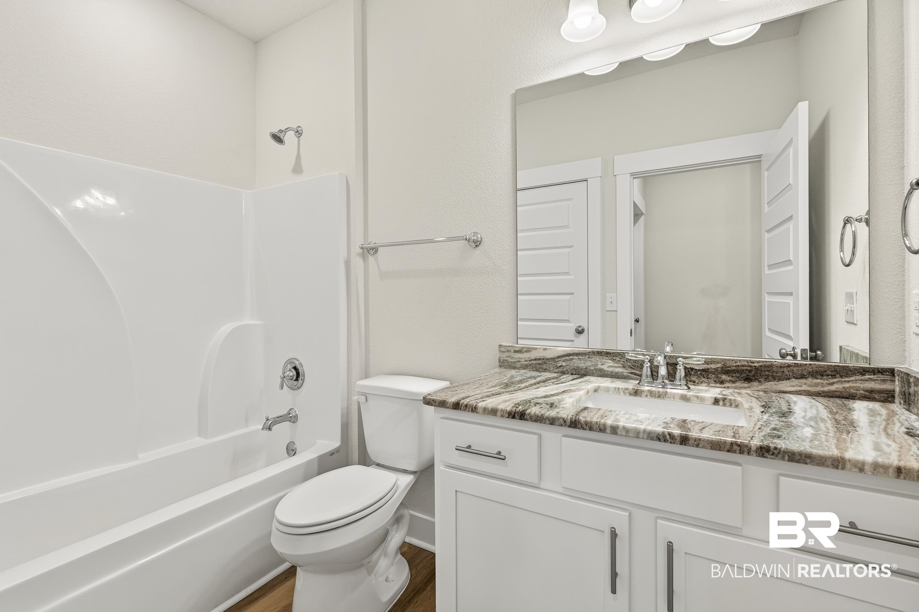 1724 Partridge Street Foley, AL 36535 - Photo 44 of 62 Bathroom featuring a white integrated tub and shower unit, a vanity with a rectangular undermount sink, a stone-finish countertop, and white cabinetry with brushed nickel hardware