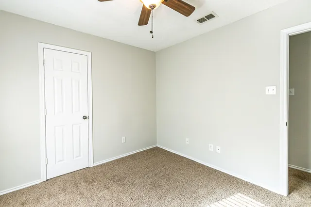 an empty room with a ceiling fan and carpet