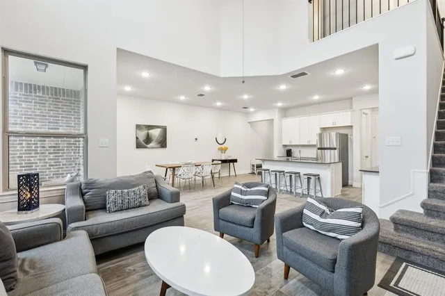 a open kitchen with stainless steel appliances kitchen island granite countertop a dining table chairs refrigerator and sink