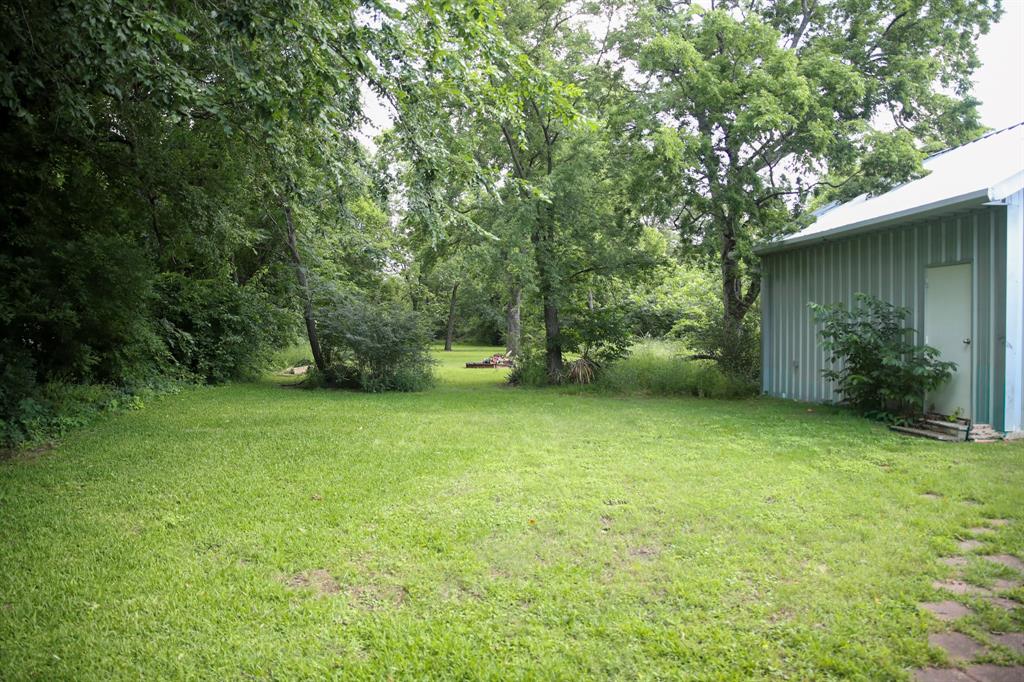 1500 Bonham Street Commerce, TX 75428 - Photo 26 of 29 a backyard of a house with plants and large trees