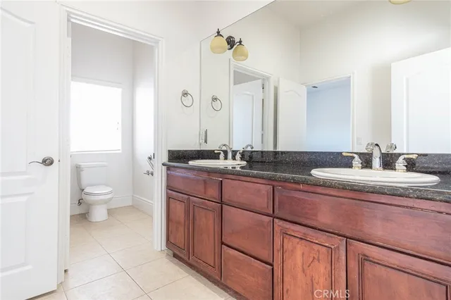 a bathroom with a granite countertop sink a toilet and a mirror