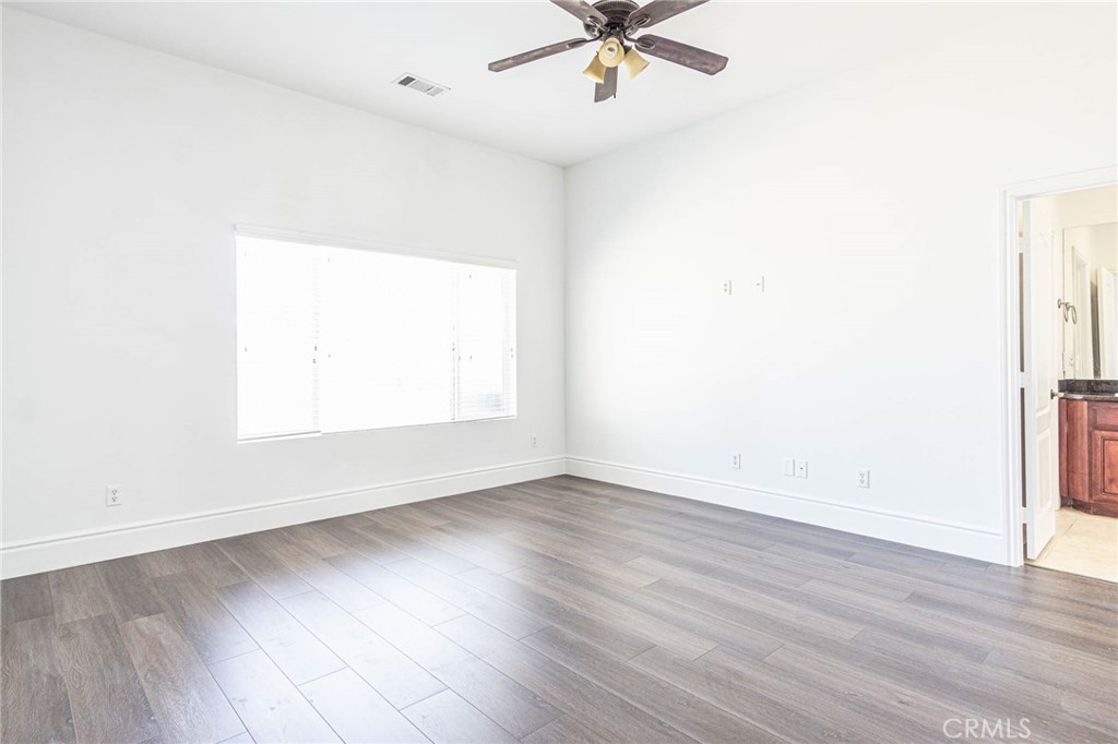 16233 Ridge View Drive Apple Valley, CA 92307 - Photo 14 of 50 an empty room with wooden floor fan and windows