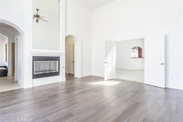 an empty room with wooden floor fireplace and windows