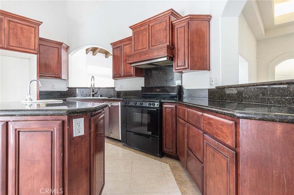 16233 Ridge View Drive Apple Valley, CA 92307 - Photo 9 of 50 a kitchen with granite countertop wooden cabinets and a stove top oven