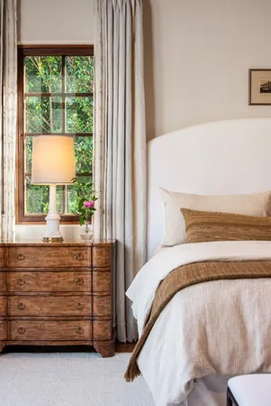 a bedroom with a bed and a dresser next to a window