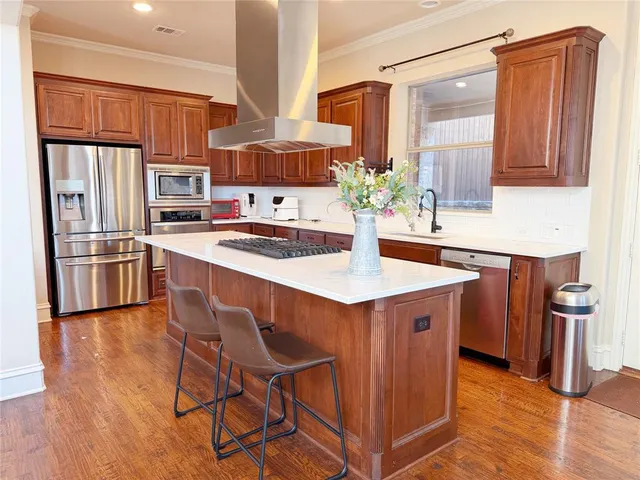 a kitchen with stainless steel appliances kitchen island granite countertop a sink refrigerator and cabinets