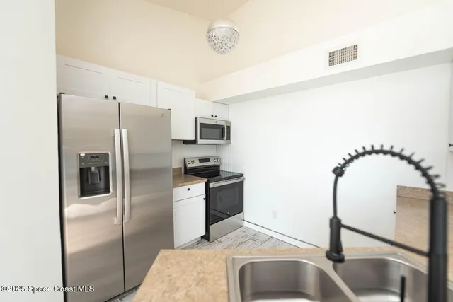 a kitchen with white cabinets appliances and a sink