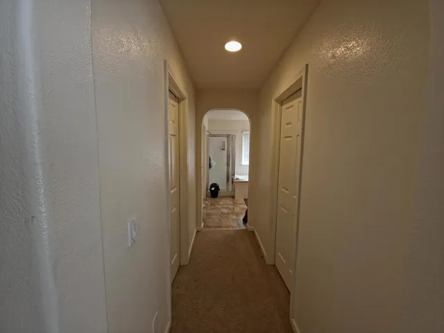 a view of a hallway with a livingroom and wooden floor