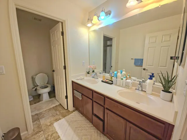 a bathroom with a double vanity sink mirror and toilet