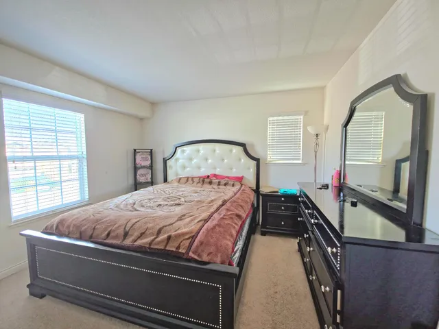a bedroom with a bed and a large mirror on the dresser