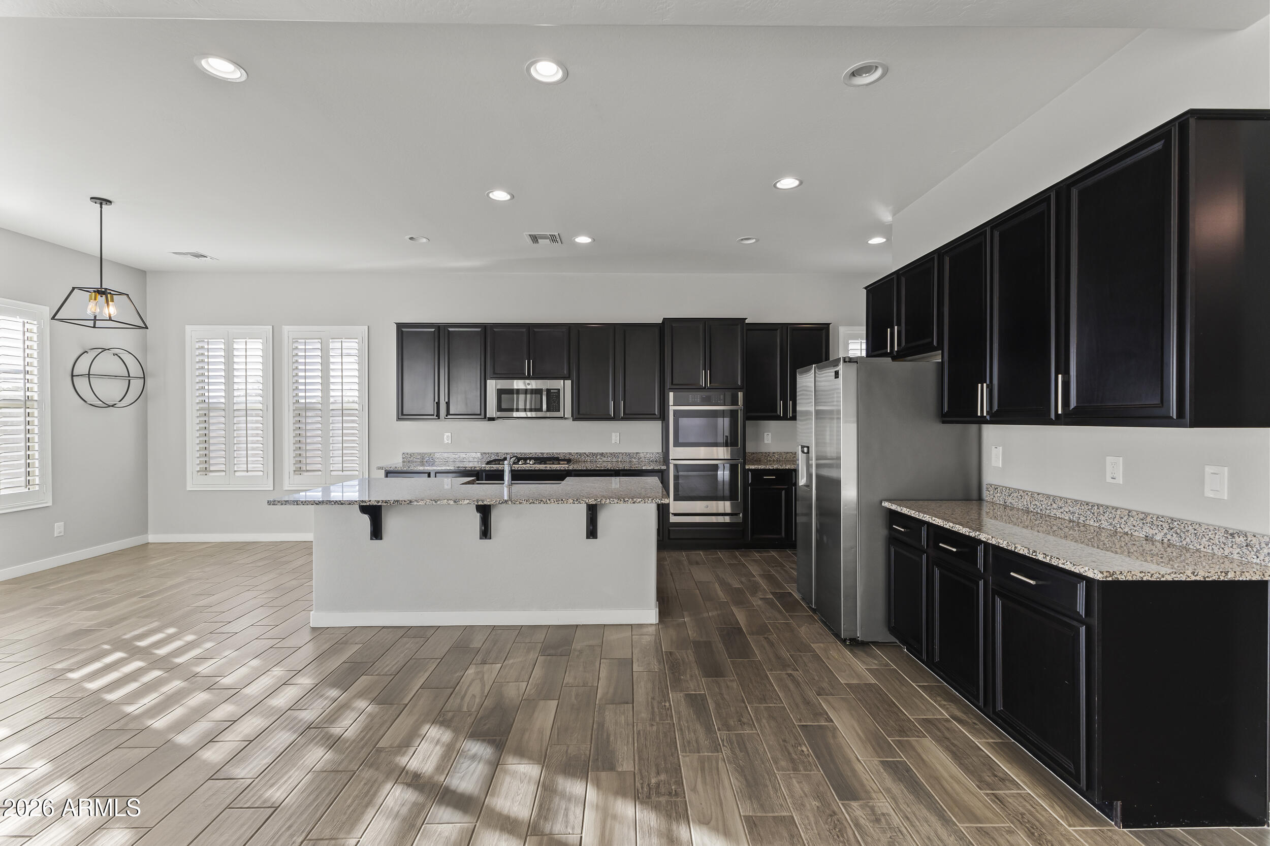 5255 North Ginning Road Litchfield Park, AZ 85340 - Photo 26 of 60 a kitchen with stainless steel appliances kitchen island granite countertop a refrigerator a sink dishwasher and a stove with wooden floor