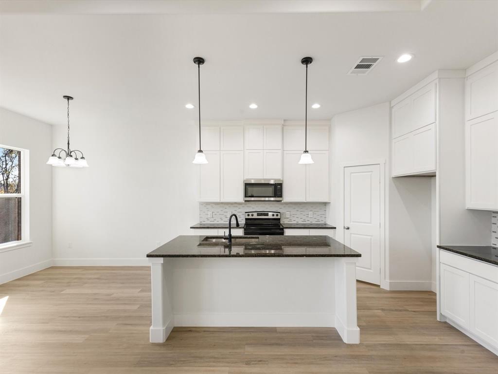 111 West Farmers Road Seagoville, TX 75159 - Photo 5 of 32 a kitchen with kitchen island stainless steel appliances sink stove and wooden floor