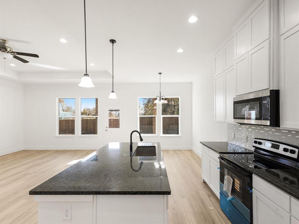 111 West Farmers Road Seagoville, TX 75159 - Photo 8 of 32 a kitchen with stainless steel appliances granite countertop a stove a oven a sink a dining table and chairs with wooden floor