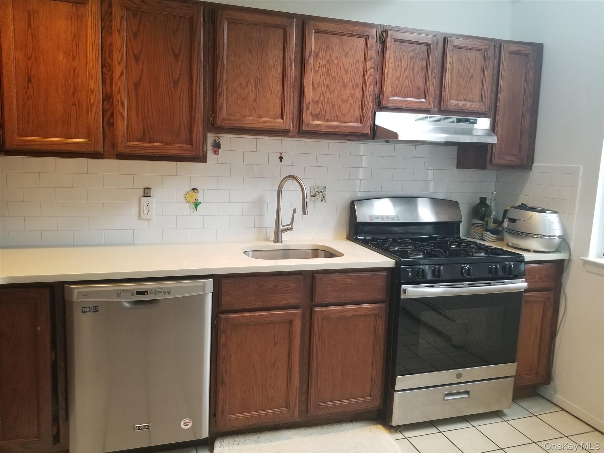70 Hickory Road, Unit B Port Washington, NY 11050 - Photo 5 of 18 a kitchen with stainless steel appliances granite countertop a sink stove and cabinets
