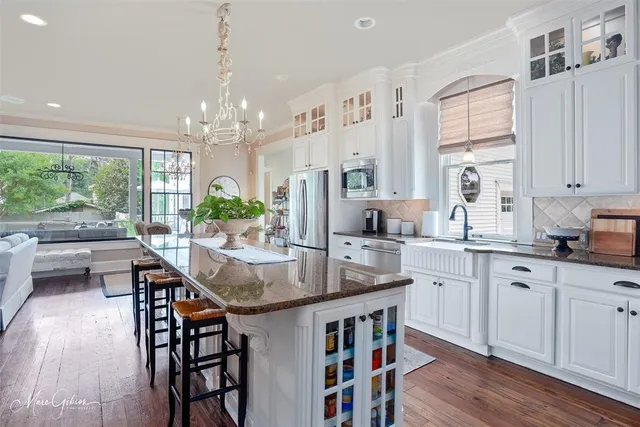 a kitchen with stainless steel appliances granite countertop a stove a sink dishwasher a dining table and chairs with wooden floor