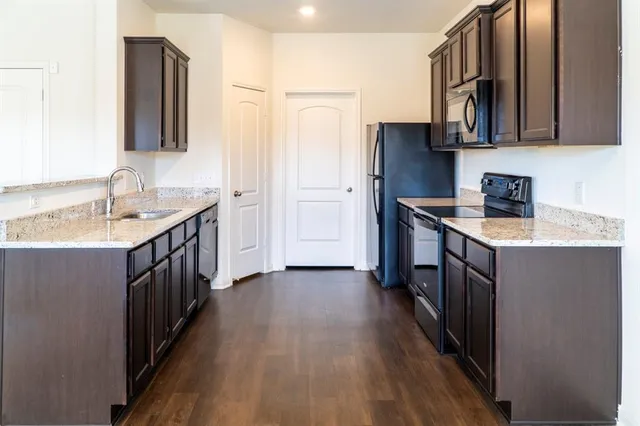 a kitchen with a sink stove top oven and wooden floor