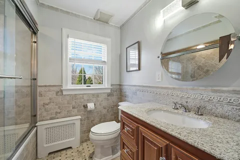 a bathroom with a granite countertop sink a toilet and a mirror