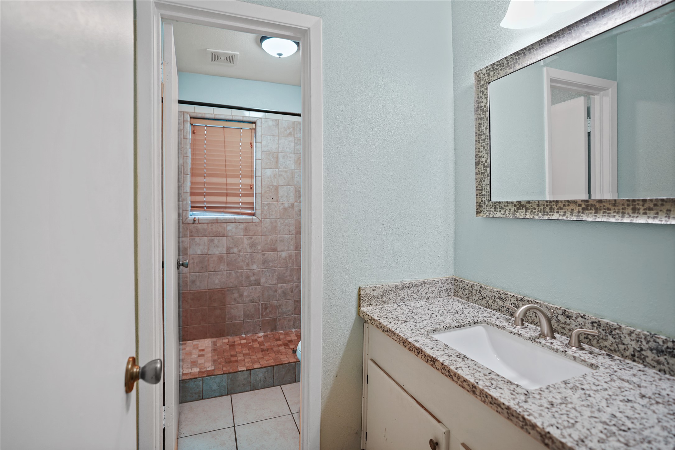 623 Rockbrook Drive Houston, TX 77015 - Photo 14 of 17 a bathroom with a granite countertop sink a mirror and shower