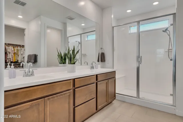 a bathroom with a double vanity sink mirror and shower