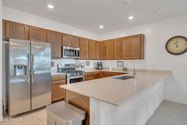 a kitchen with stainless steel appliances granite countertop a sink a stove a refrigerator a center island and a refrigerator