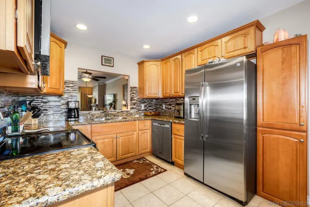 a kitchen with stainless steel appliances granite countertop a refrigerator a sink and white cabinets