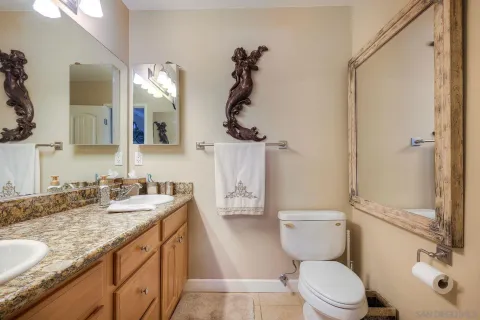 a bathroom with a granite countertop toilet sink and mirror