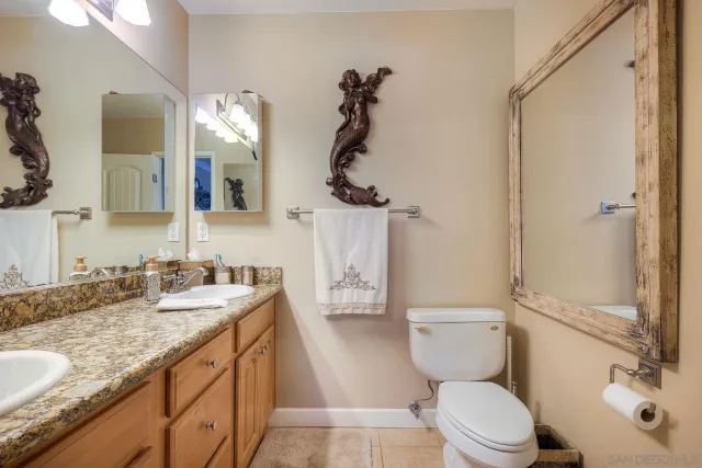 a bathroom with a granite countertop toilet sink and mirror