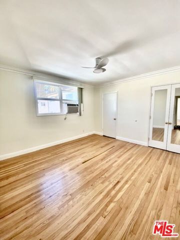 a view of empty room with wooden floor and fan