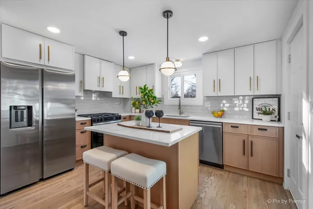 a kitchen with stainless steel appliances granite countertop a sink a stove a refrigerator and island with wooden floor