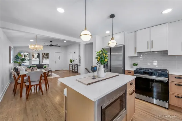 a kitchen with a dining table cabinets appliances and wooden floor