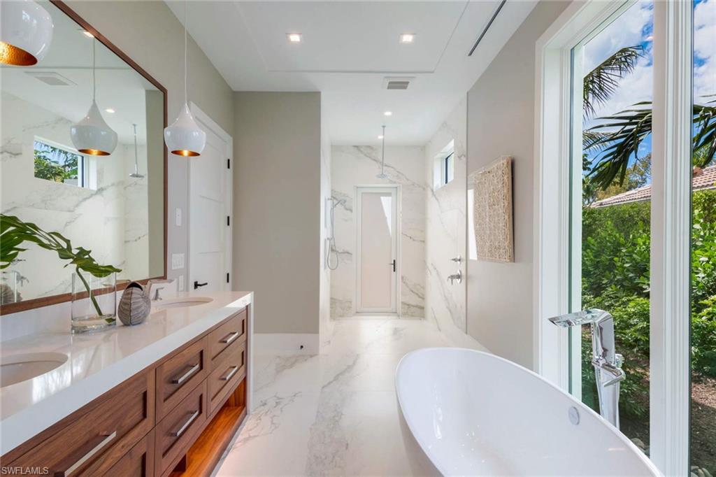 1430 Crayton Road Naples, FL 34102 - Photo 20 of 34 a spacious bathroom with a double vanity sink a large mirror a bathtub and shower