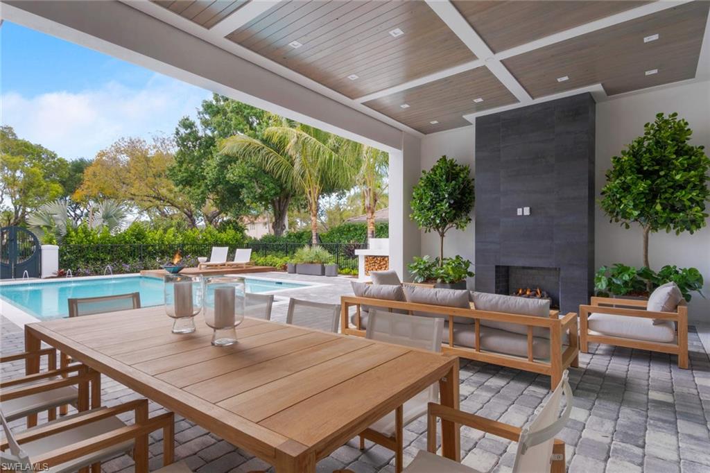 1430 Crayton Road Naples, FL 34102 - Photo 23 of 34 a view of a patio with a dining table and chairs with wooden floor and fence