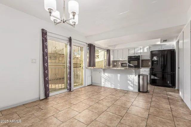 a large white kitchen with a stove a refrigerator cabinets and a dining table