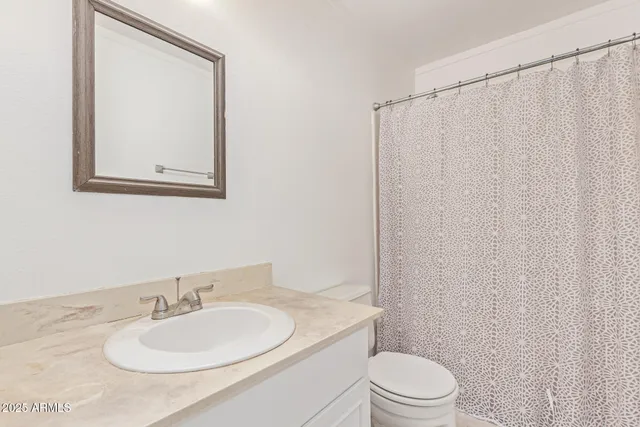 a bathroom with a sink vanity mirror and toilet