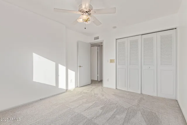 an empty room with a ceiling fan and a window