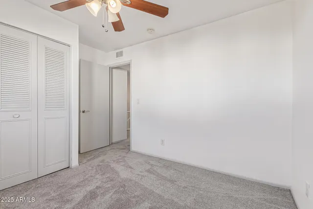 an empty room with a ceiling fan and closet