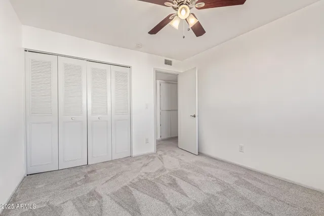 an empty room with a chandelier fan and windows
