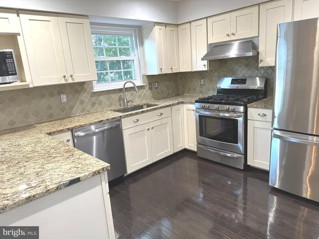 a kitchen with granite countertop a sink stainless steel appliances and cabinets